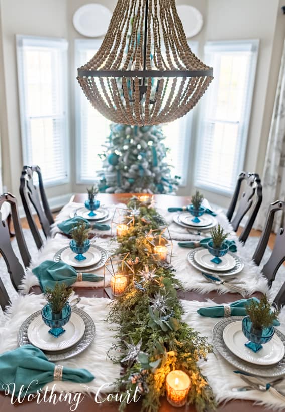 A beaded chandelier above the decorated tablescape with lit candles on the table.