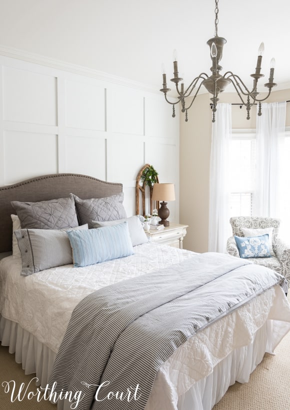 The bedroom painted white with white an neutral bedding and the chandelier over the bed.