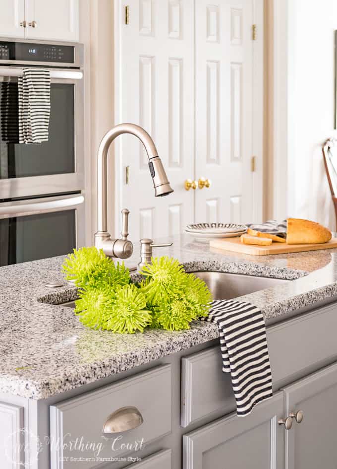 Kitchen sink with bright green flowers lying beside it.