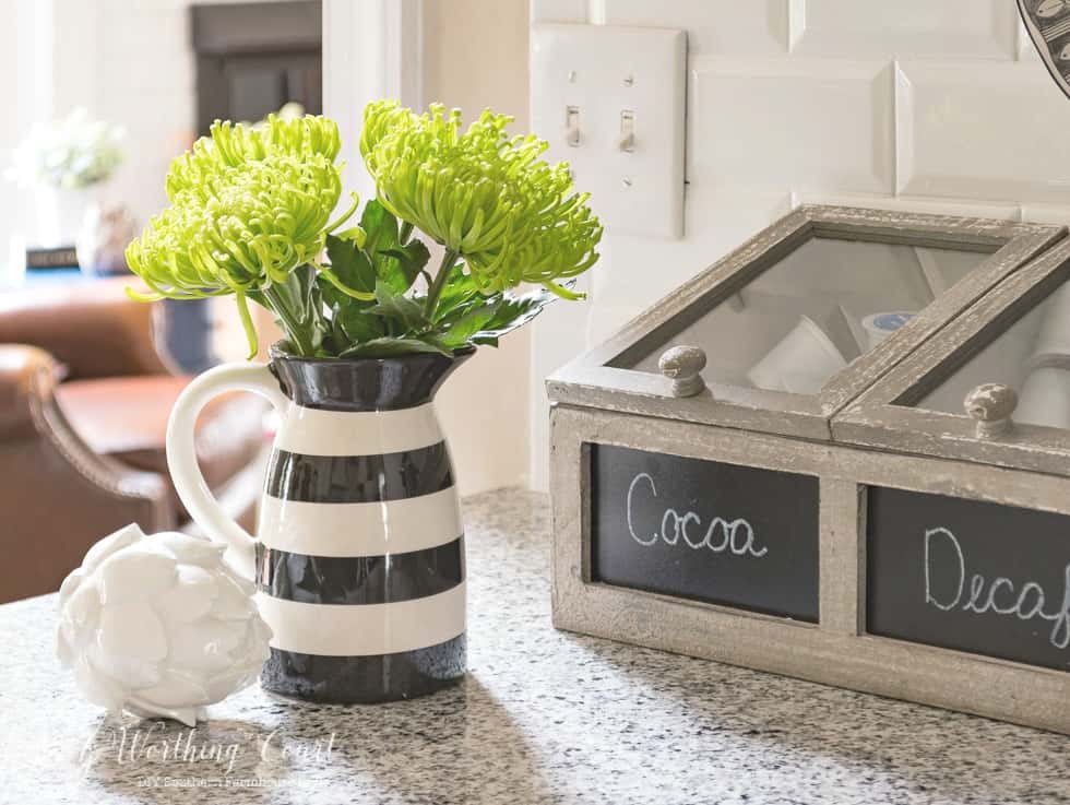 Black and white pitcher filled with bright green flowers.