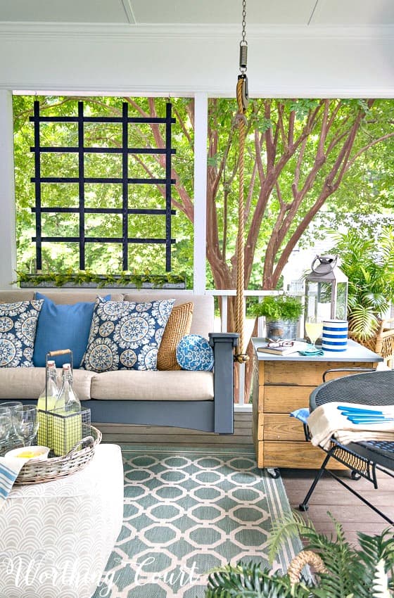 Porch swing with blue and white throw pillows.