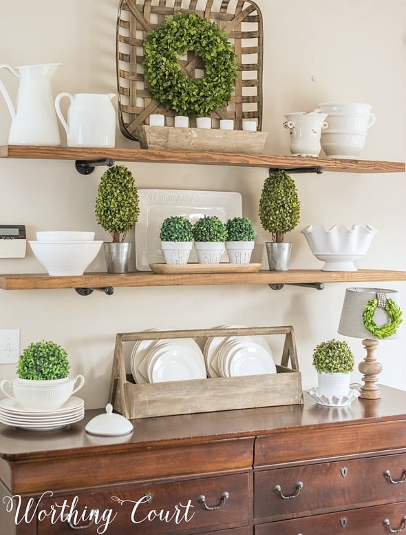 Open shelves decorated with white dishes and greenery.