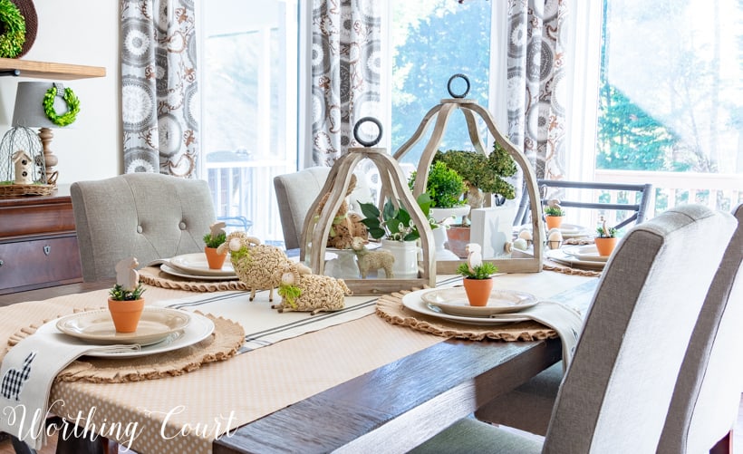 The Easter table setting with white plates and mini potted plants on the plates.