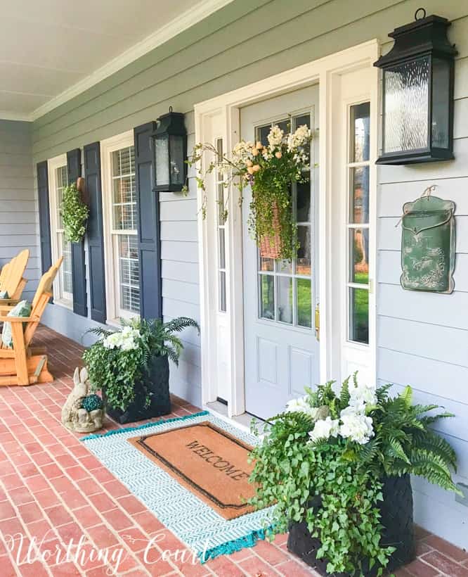 front porch with gray siding and gray front door flanked by planters