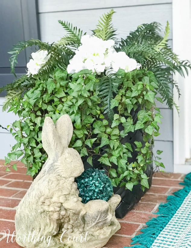 black basket planter with green ivy and a decorative rabbit