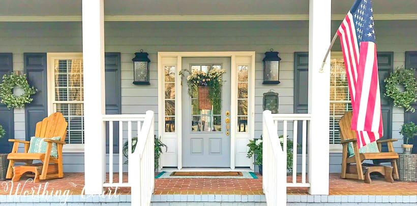 front porch with gray siding, white columns and a gray front door with sidelights