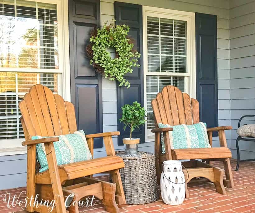 pair of wood stained adirondack chairs on front porch with gray siding