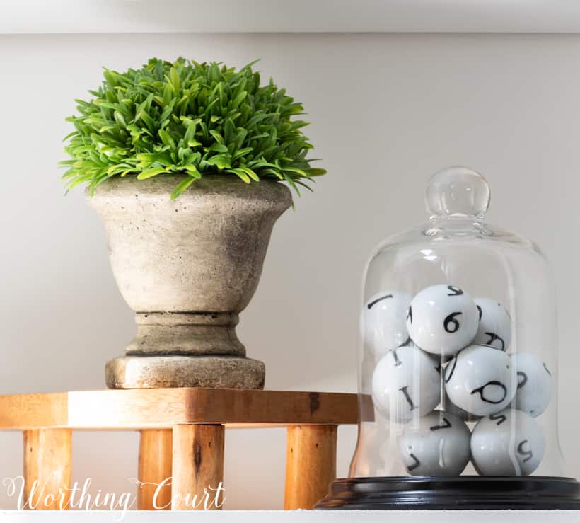 Bookcase vignette with faux greenery and a glass cloche.