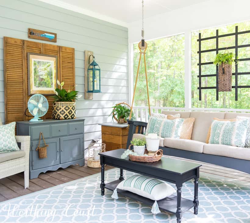 Screen porch decor with hand painted furniture and a blue and white area rug.