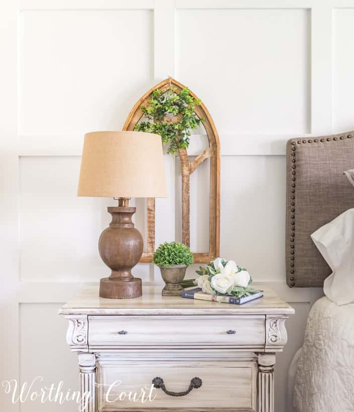 white nightstand with wood lamp and gothic arch art