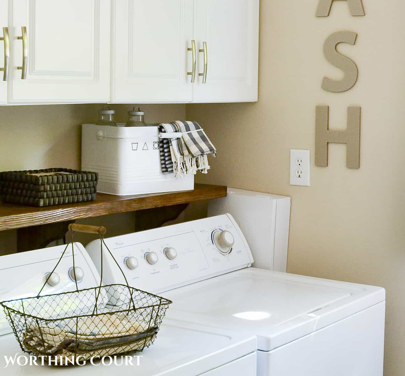 top of white washing machines with a white box on the wall to hide the washer connections