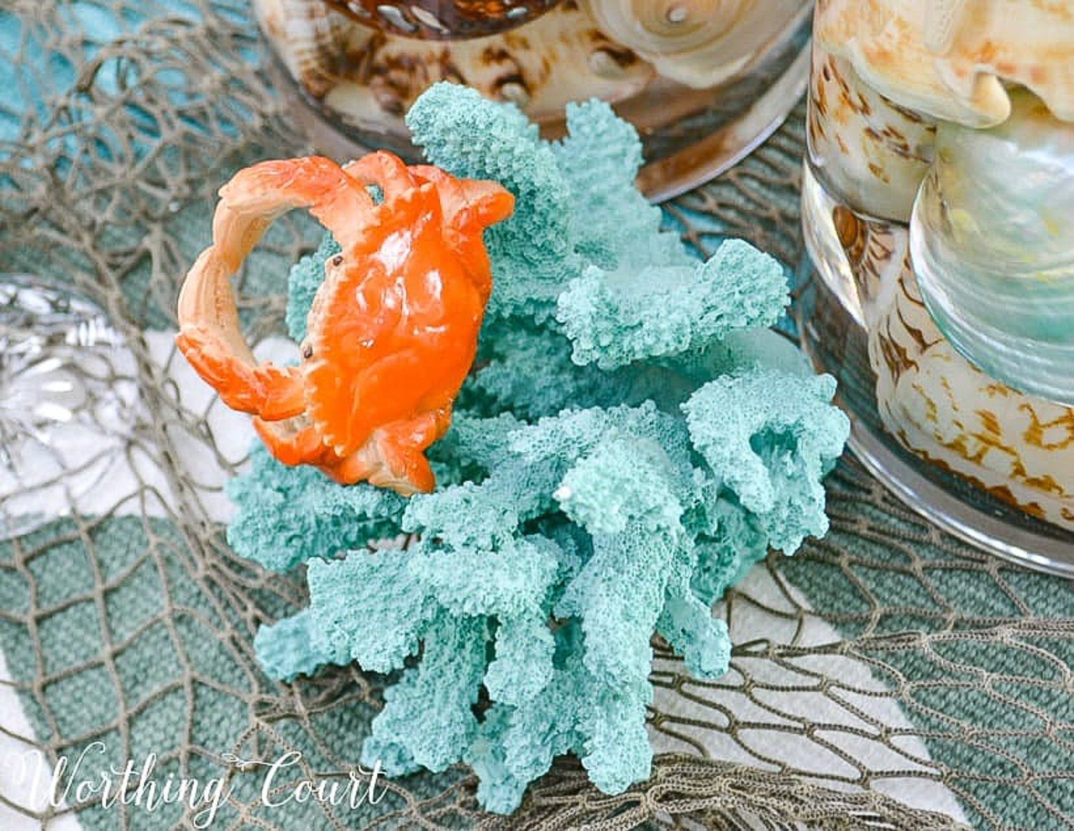 outdoor dining table set with a coastal theme using blue and coral dishware and coastal accessories