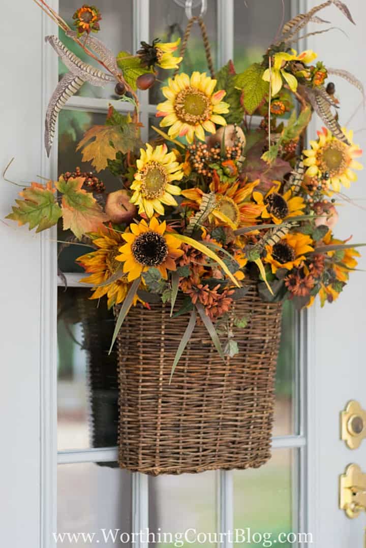 Hanging basket filled with artificial fall floral stems in shades of yellow orange and green.