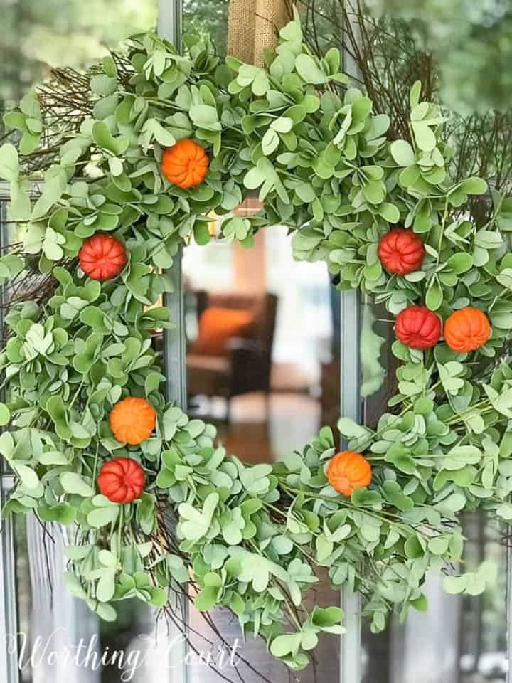 green eucalyptus wreath embellished with faux pumpkins 