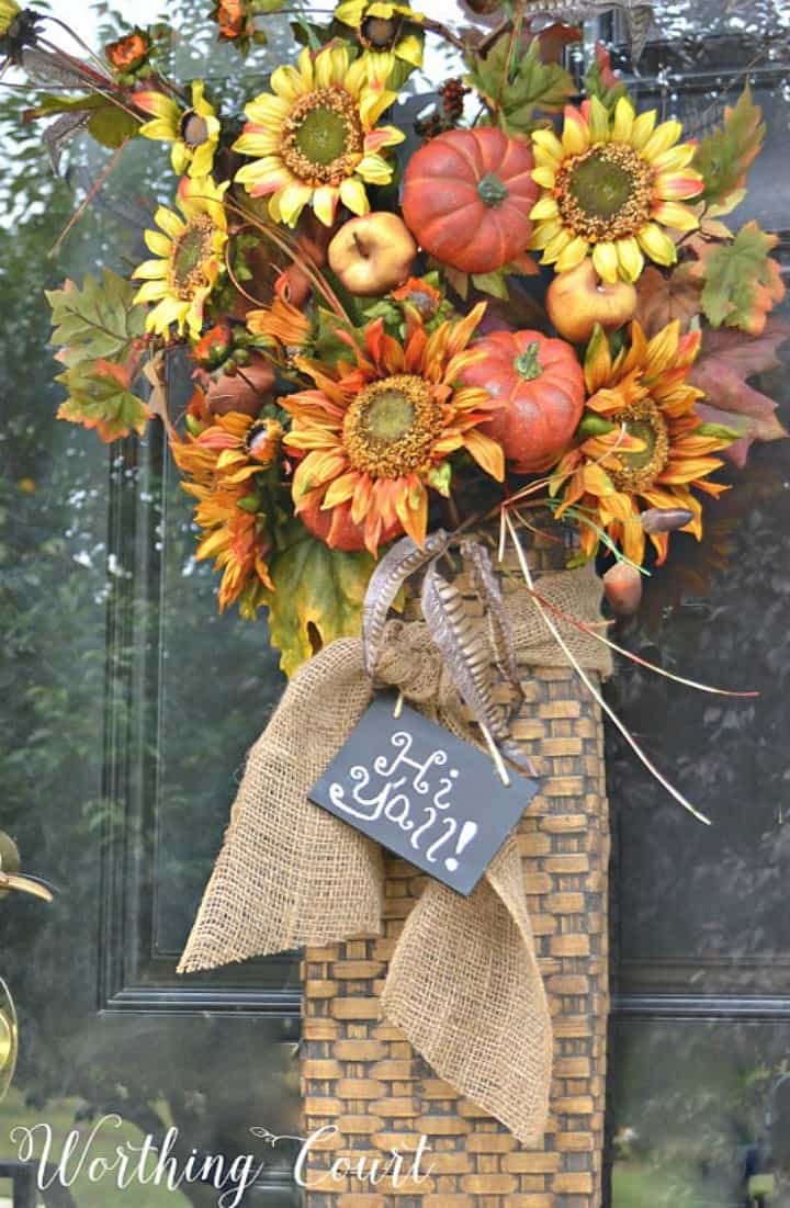 cesta colgante en la puerta de entrada llena de tallos florales de otoño