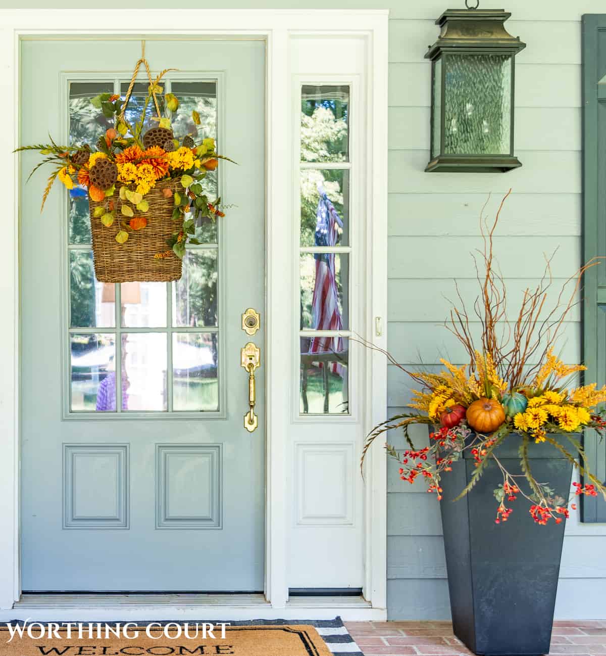 gray front door with hanging basket and planter filled with fall foliage