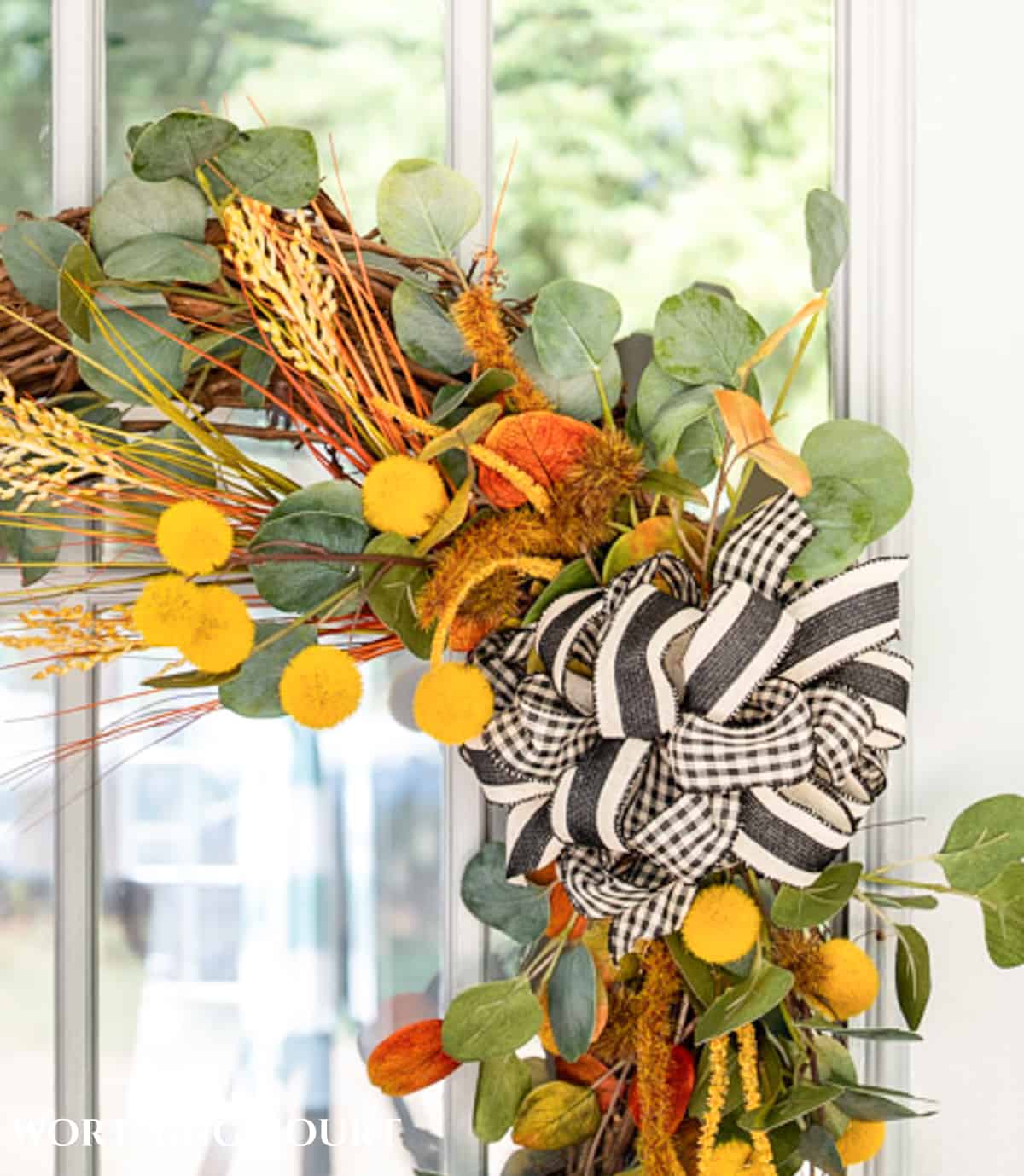 one corner of a diy fall wreath made with traditional fall colors and a black and white bow