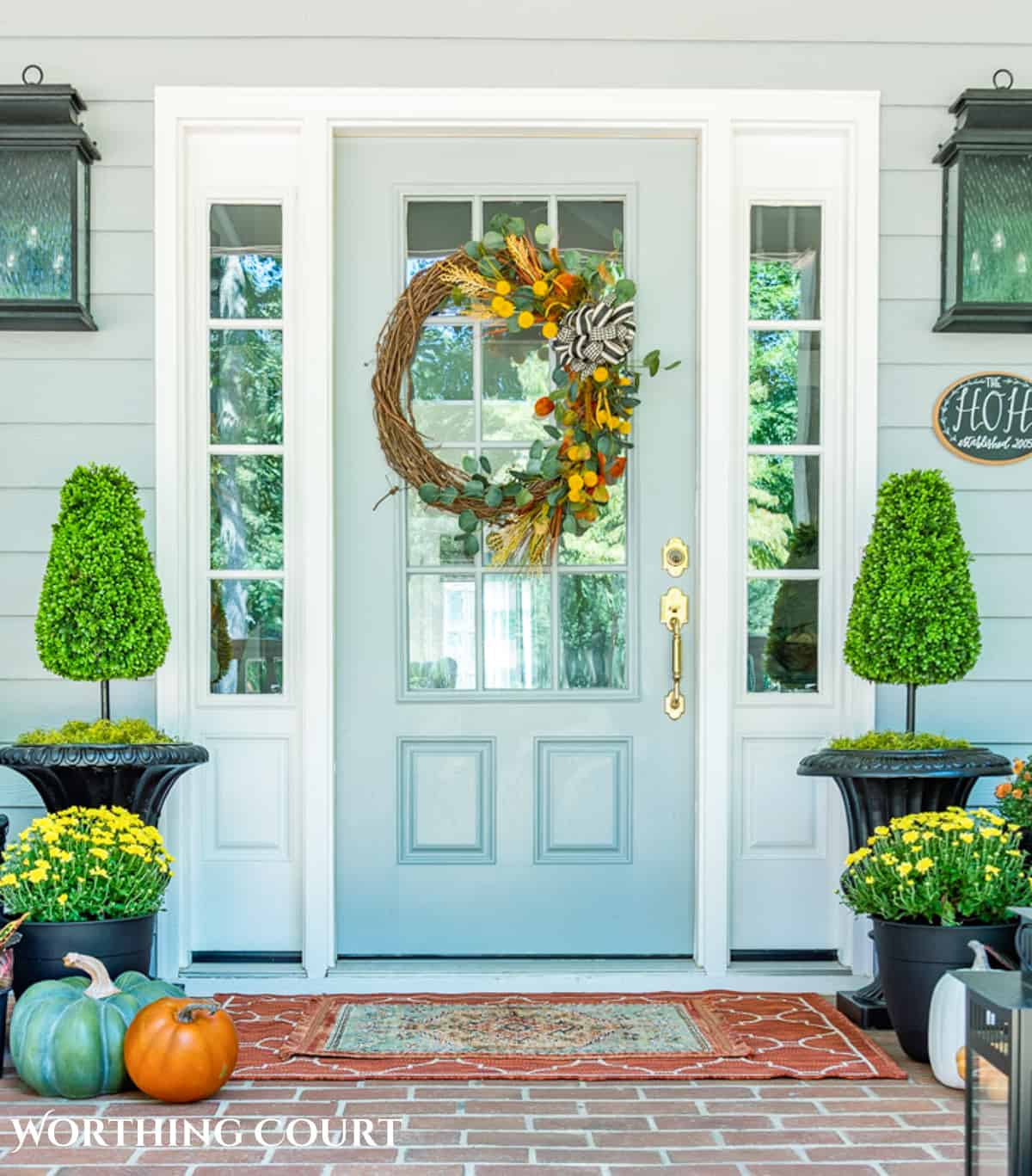 diy fall grapevine wreath with traditional fall colored picks on a gray front door