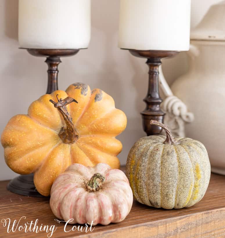 trio of faux pumpkins on a shelf in muted fall colors