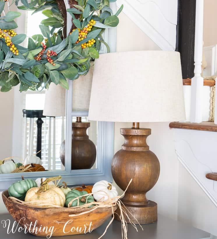 fall entry table decor with pumpkins in a wooden bowl