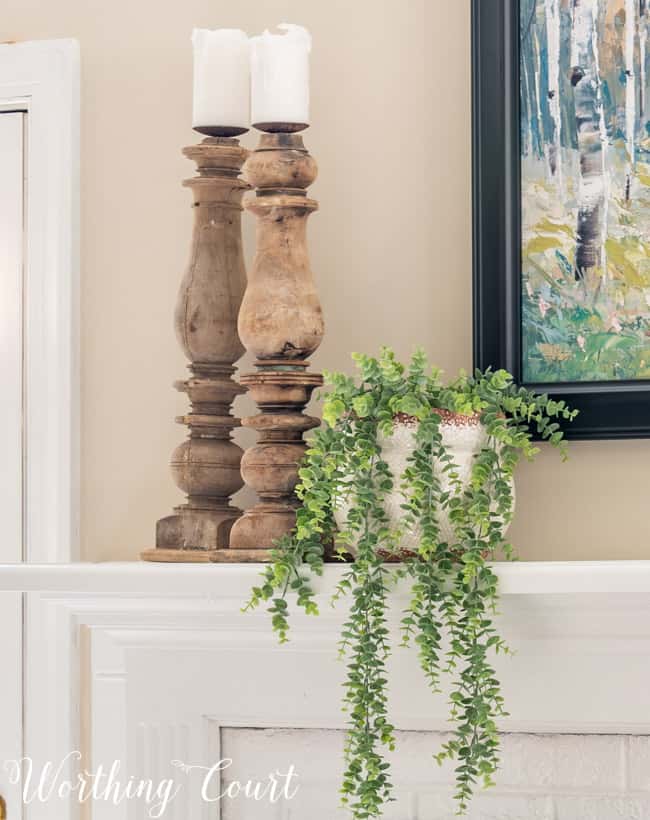 Natural wood candlesticks and trailing greenery on a mantel.