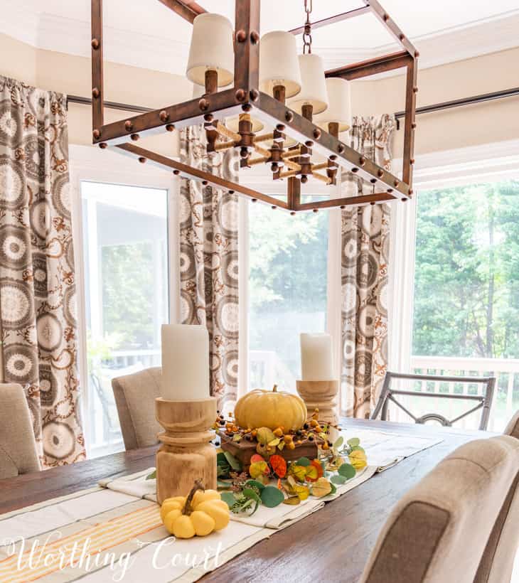 fall centerpiece with chunky candles, a faux pumpkin and muted fall colors