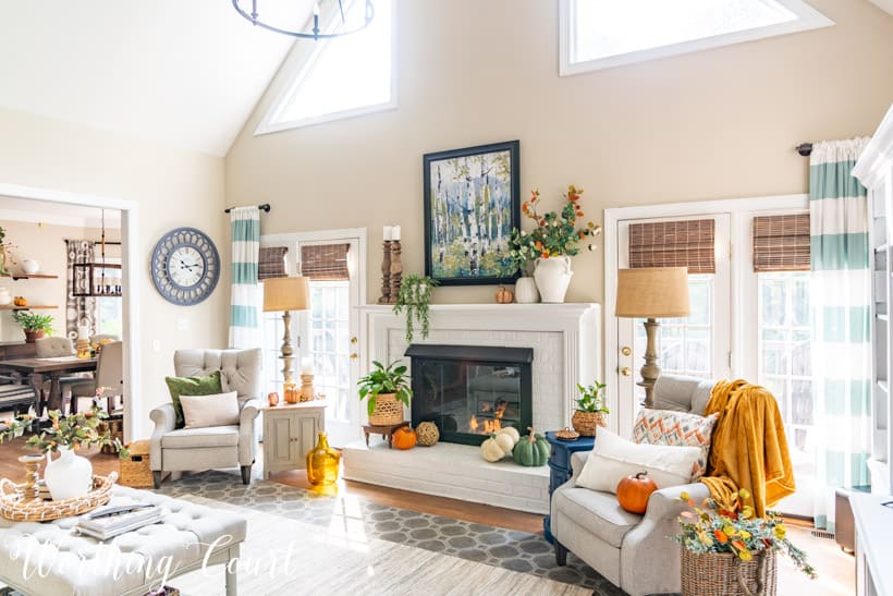 Neutral living room and white painted brick fireplace with fall decor.