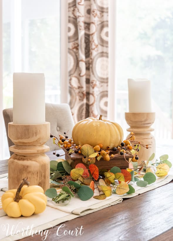 fall centerpiece with chunky wood candlesticks and faux eucalyptus in fall colors