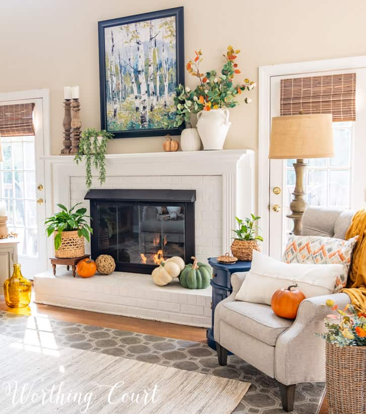 White brick fireplace decorated with traditional fall colors.