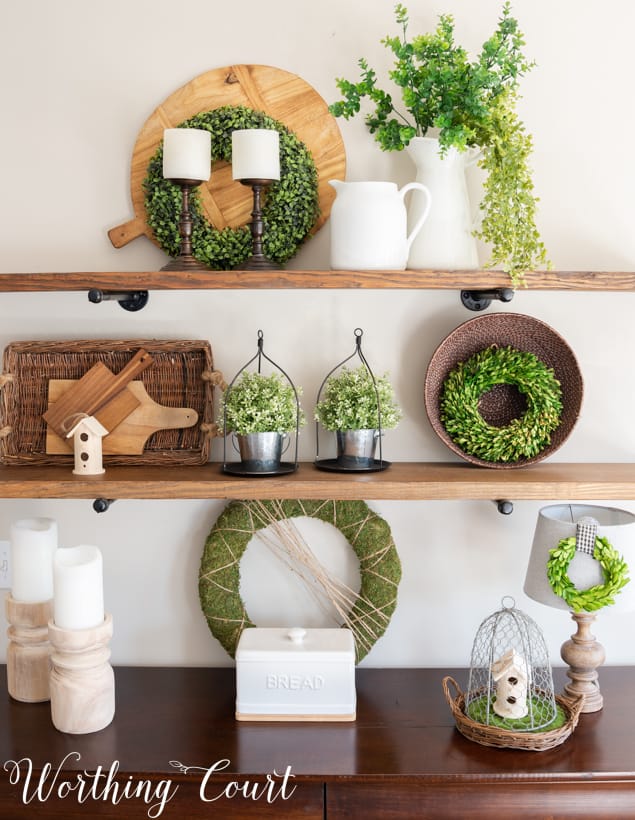 The various texture of decor items on the shelf, such as the greenery, plus porcelain, and wicker baskets on the shelf.
