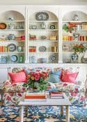 floral upholstered couch and a pair of lamps in front of built-in white shelves in a living room decorated with colorful, traditional living room type accessories