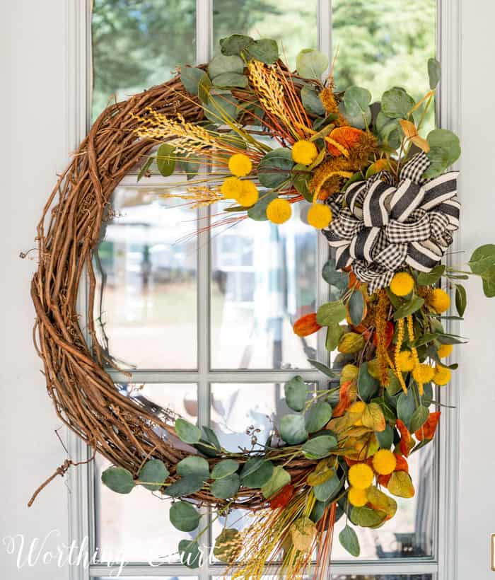 front porch decor ideas including a grapevine wreath with colorful fall picks and a black and white bow