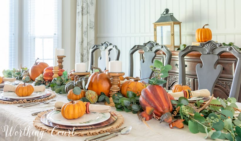 thanksgiving table set with orange pumpkins and eucalyptus on a linen tablecloth