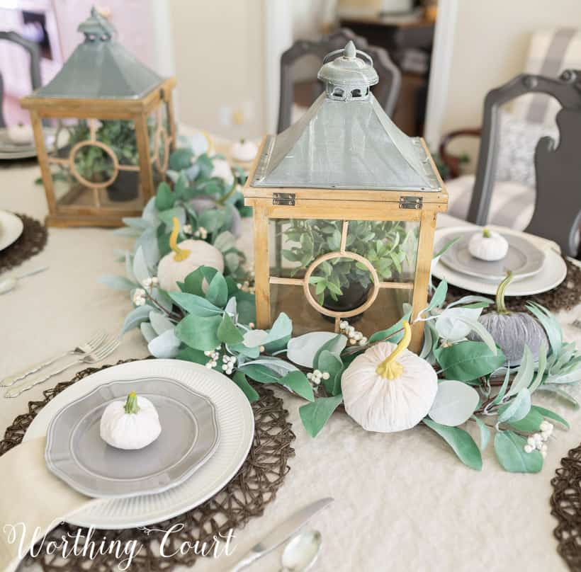 Table set for Thanksgiving with neutral linens and dishes and lanterns