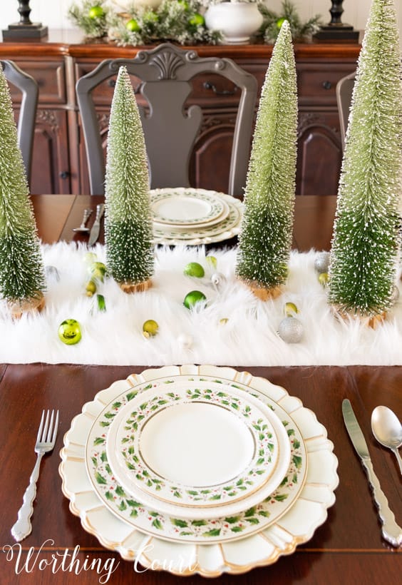 Christmas place setting with ivory plates with holly leaves and a gold rim.