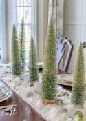 dining room table set for Christmas with green, silver and gold
