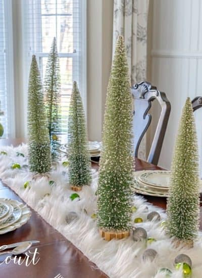 dining room table set for Christmas with green, silver and gold