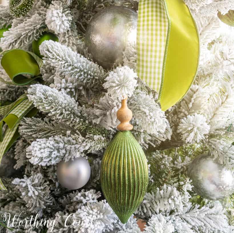 A soft green ornament with a wooden top beside green ribbon on the tree.