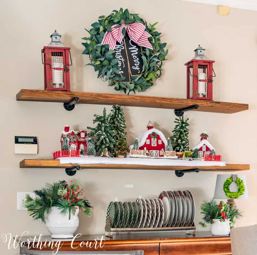 A eucalyptus wreath with a red and white bow on the wooden shelving unit.