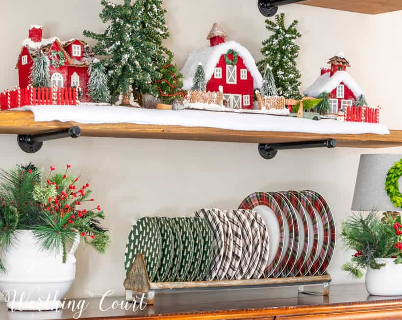 Plate rack on top of sideboard filled with Christmas plaid dishes.