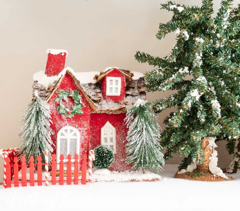 Red Christmas mini house on a bed of faux snow.