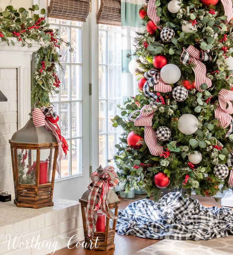 A lantern with a red candle in it is beside the Christmas tree.