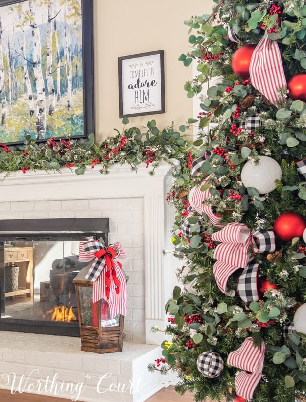 There is a eucalyptus garland on the white fireplace mantel.