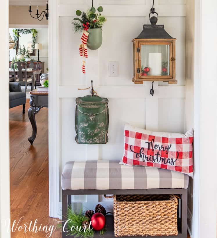 A red and white checkered pillow is in the corner on the bench that says Merry Christmas.