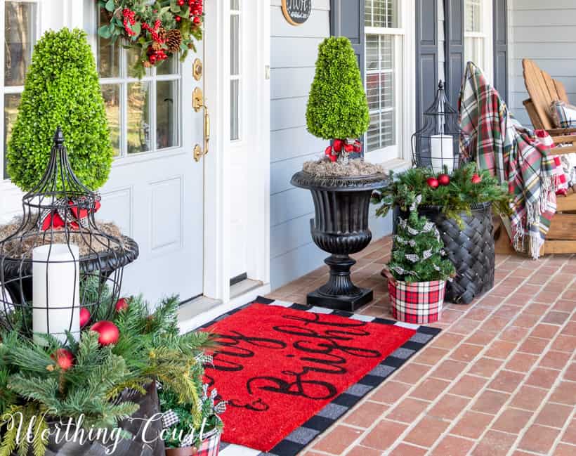 Urns filled with topiaries decorated for Christmas with red, black and white ribbon.