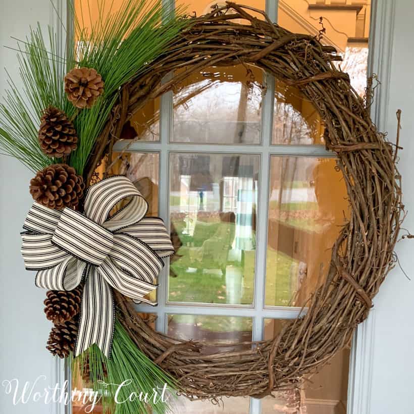 grapevine wreath with pine branches and black and white bow