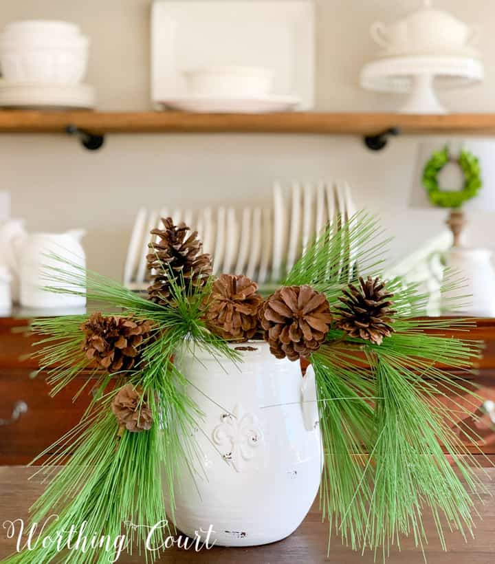 white vase filled with faux pine branches