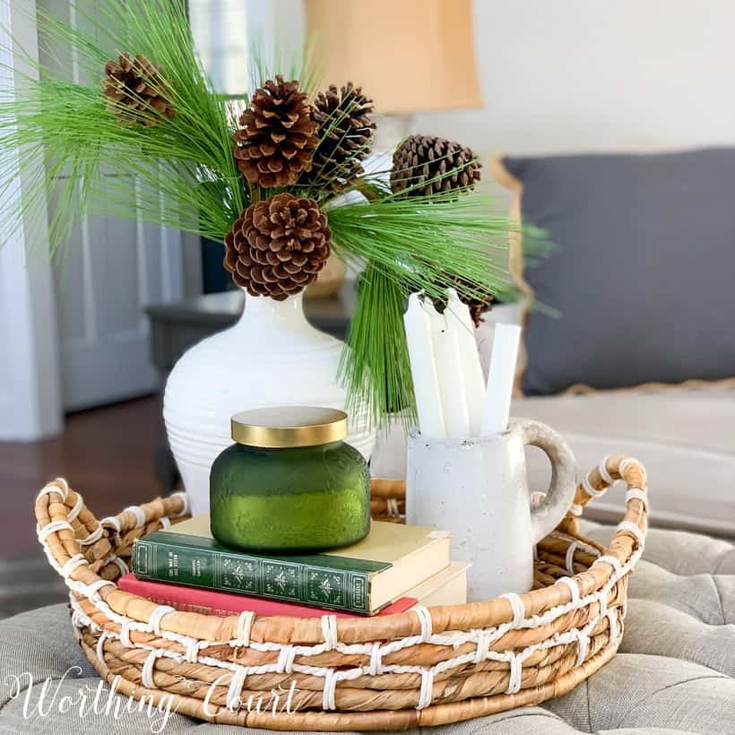 woven tray with white vase filled with evergreens