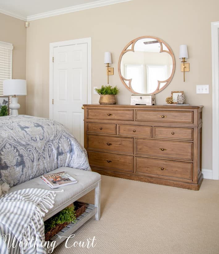 dresser with round mirror above flanked with brass sconces