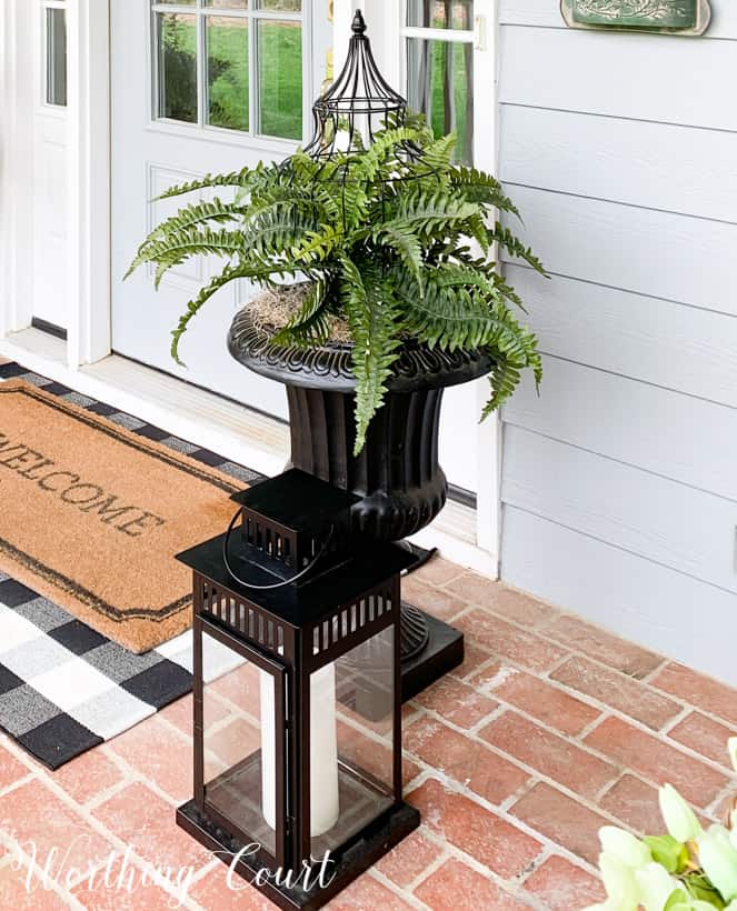 There is an urn by the front door with a fern in it.